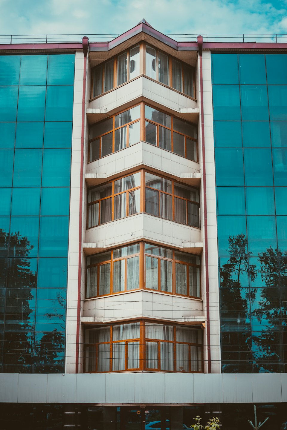 Moderná budova s drevenými oknami a modrými sklenenými panelmi.